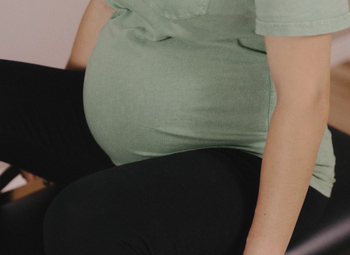 Gros plan sur un ventre de femme enceinte pendant une séance privée de Pilates prénatal à Saint-Henri, Montréal.