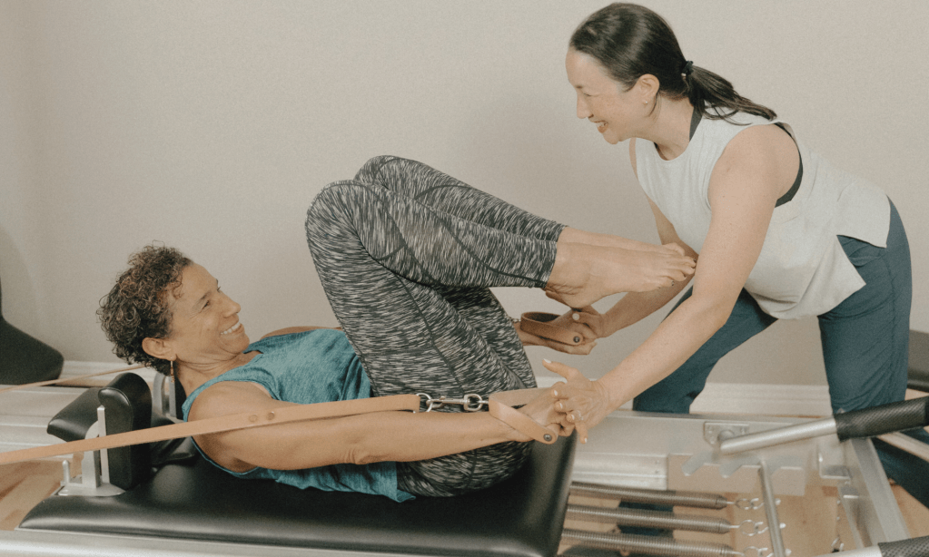 Séance privée de Pilates sur le Reformer avec l'instructeur guidant un client dans l'exercice du Hundred au studio Cadance à St-Henri, Montréal.